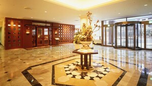 A lobby with a marble floor, a central floral arrangement, and a revolving door. - Sapporo Excel Hotel Tokyu (Sapporo)