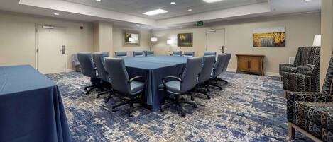 A conference room with a large table, chairs, and a carpeted floor.