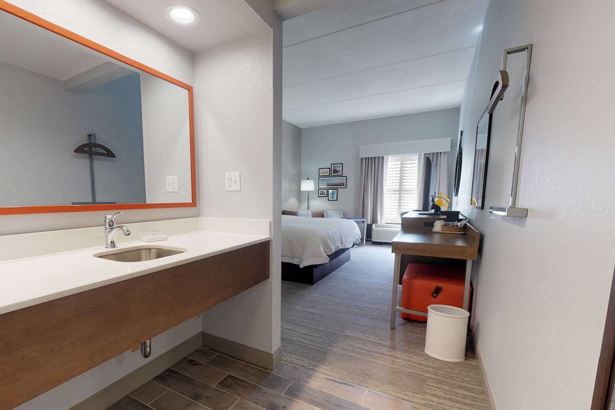 A hotel bathroom with a large mirror, sink, and a shower area.