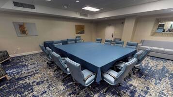Una sala de conferencias con una gran mesa, sillas y una alfombra estampada.