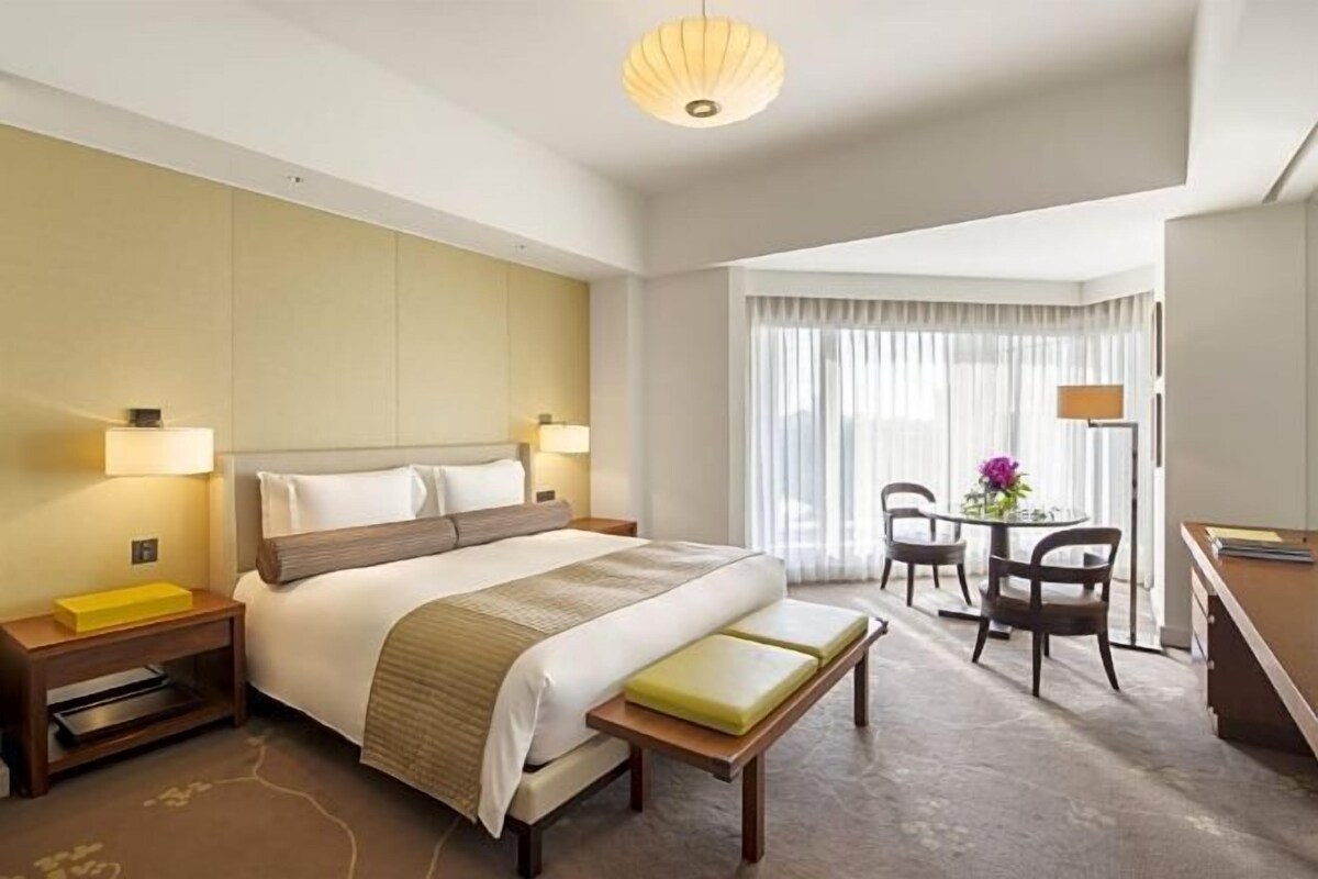 A hotel room with a large bed, bedside tables, a desk, and a chair.