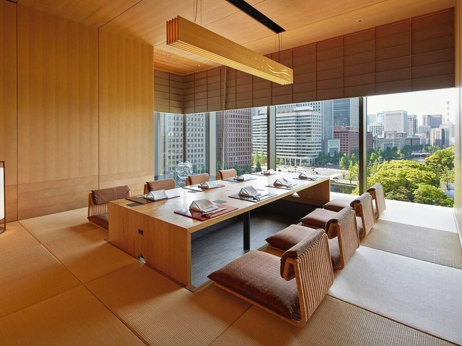 A modern meeting room with a large table, chairs, and tatami mats.