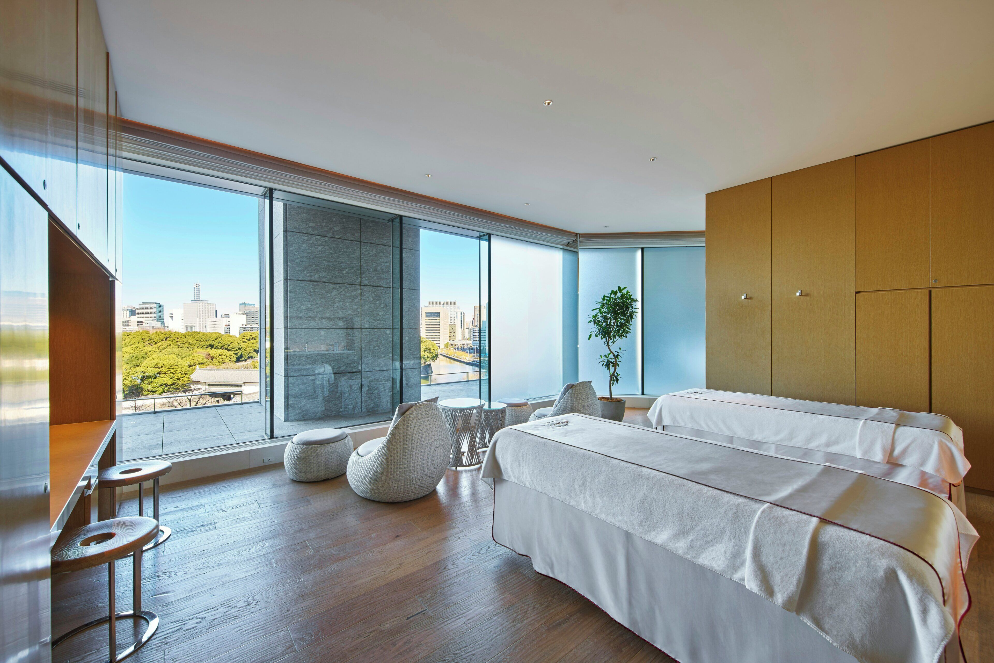 A modern bedroom with a large bed, a seating area, and a view of the city.
