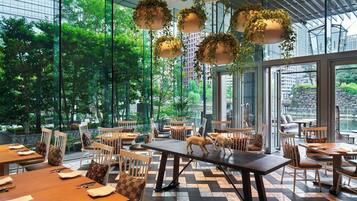 A restaurant with large windows, wooden tables, and hanging plants.