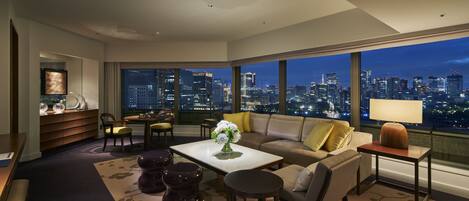 A modern living room with a city view, a sofa, a coffee table, and a dining area.