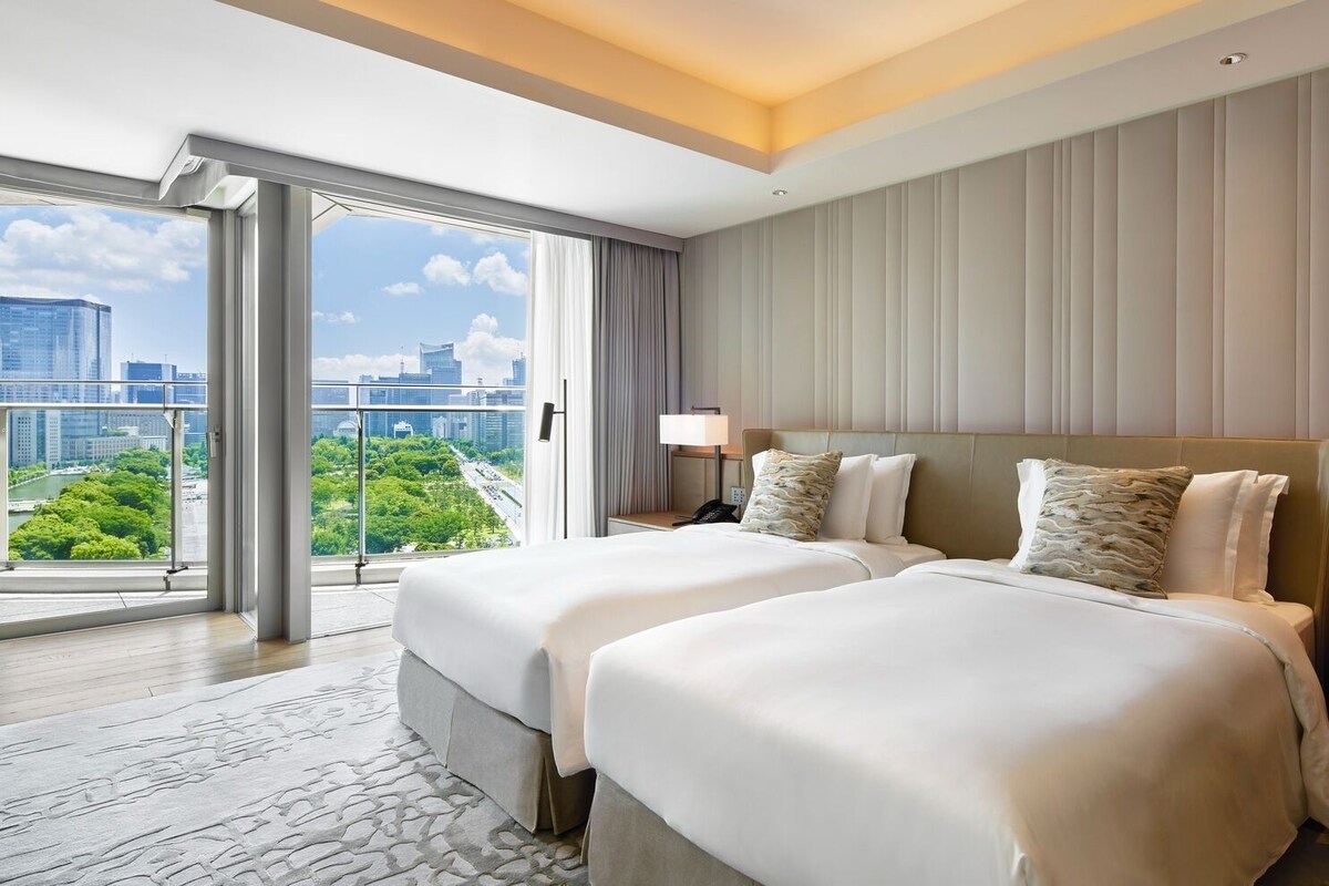 A hotel room with two beds, a city view, and a balcony.