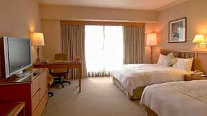 A hotel room with two beds, a desk, a television, and a window with curtains. - First Hotel (Taipei)
