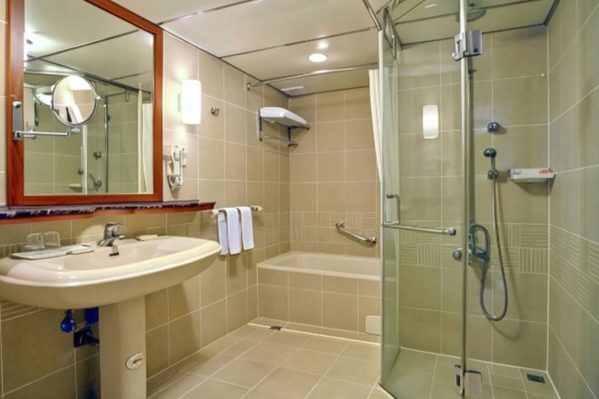 A bathroom with a sink, mirror, shower, and bathtub.
