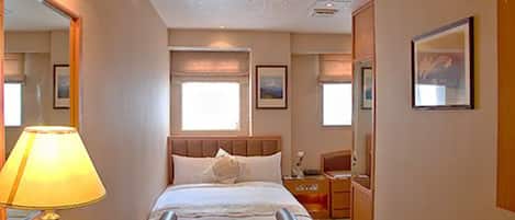 Une chambre d’hôtel avec un lit, une table de chevet, une lampe et un grand miroir.