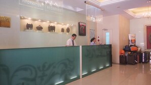 A reception area with a reception desk, a digital display, and a wall with cultural artifacts. - First Hotel (Taipei)