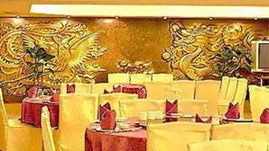 A restaurant with round tables covered in red tablecloths and yellow chairs. - First Hotel (Taipei)