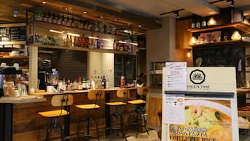 A restaurant interior with a bar area, wooden bar stools, and a menu board advertising omellette rice.