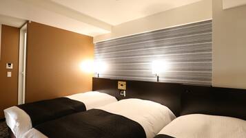 A hotel room with a large bed, a headboard with a light fixture, and a wall with a striped pattern.