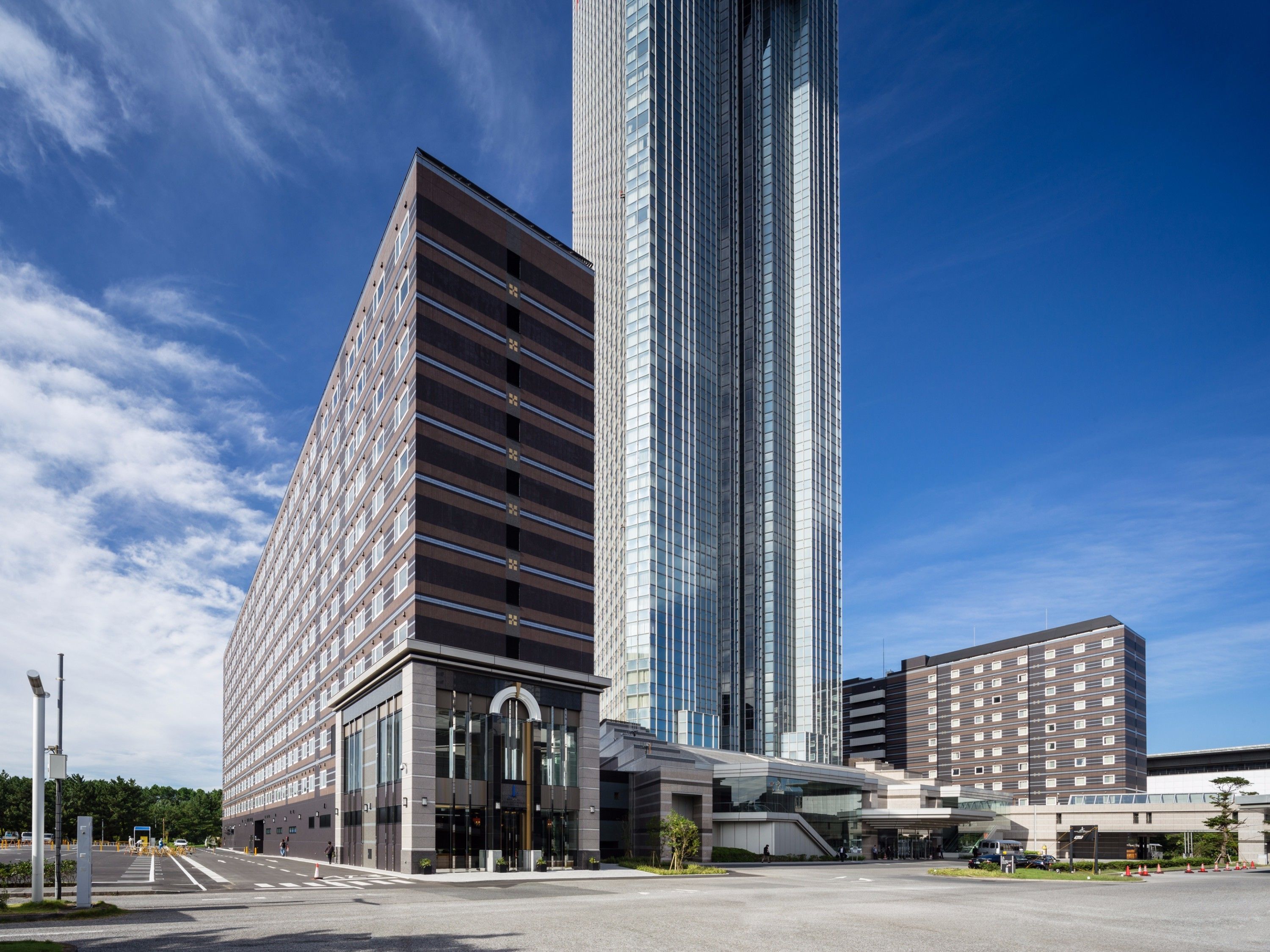 Un hotel moderno con una torre centrale e un parcheggio.