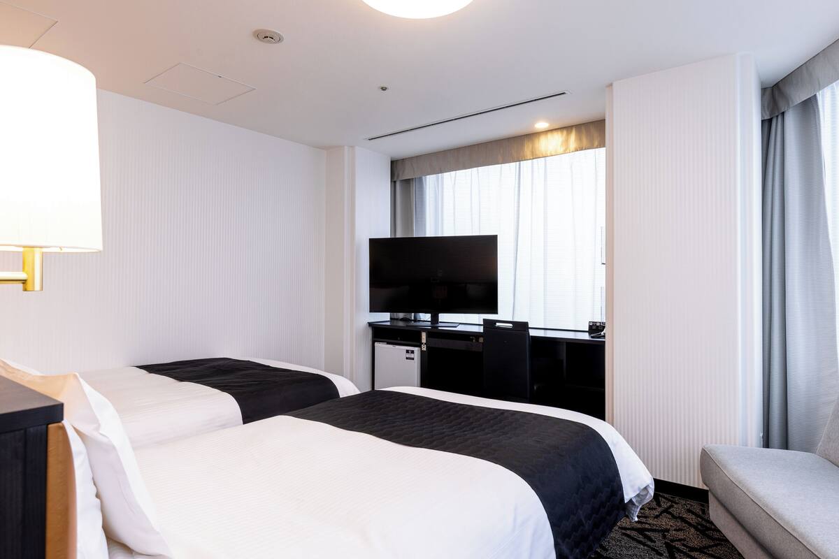 Ett hotellrum med två sängar, ett skrivbord med en tv och en sittgrupp.