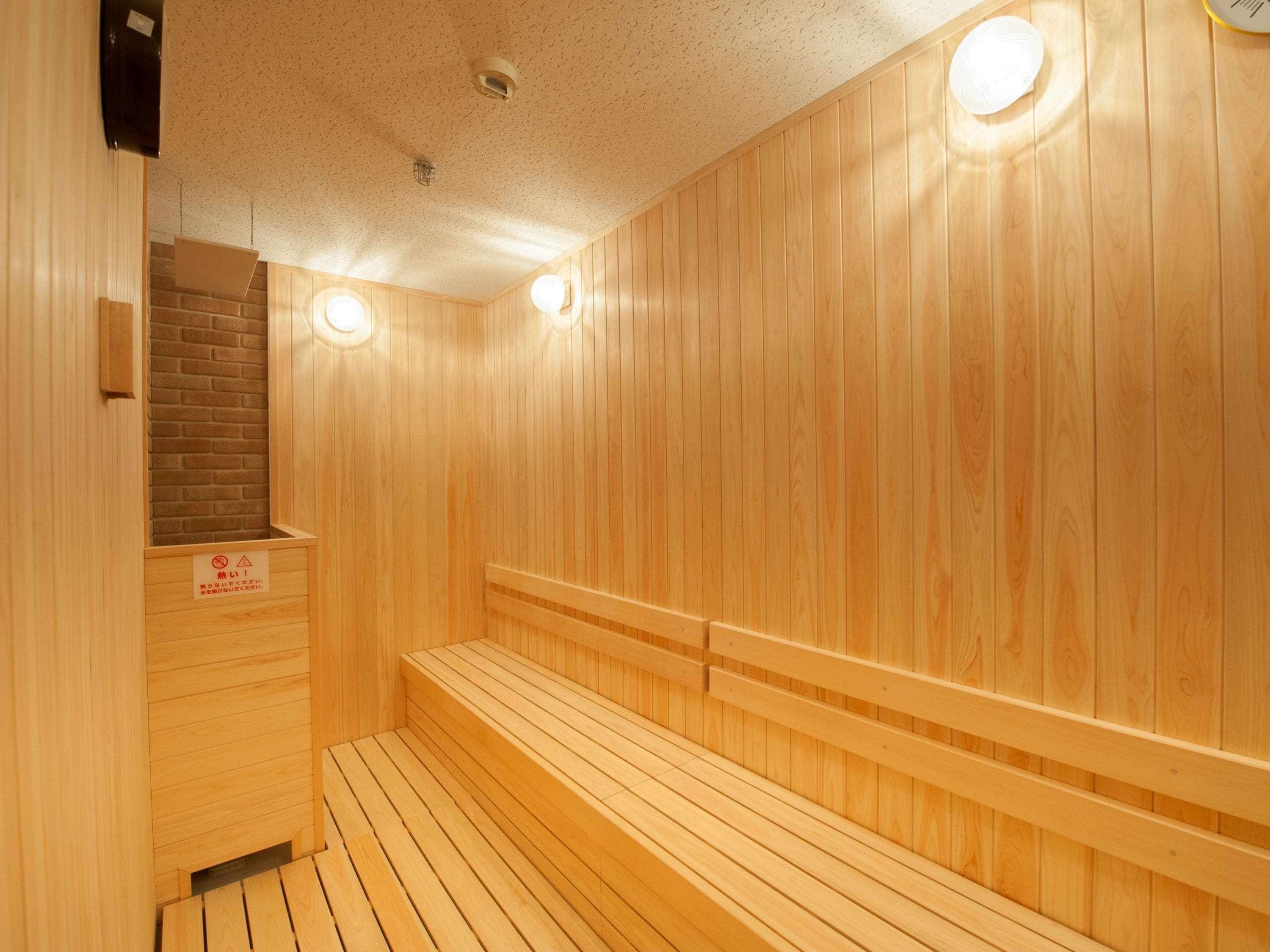 A wooden sauna with benches and a brick wall.