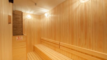 A wooden sauna with benches and a brick wall.