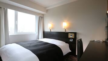 A hotel room with a bed, two bedside lamps, a control panel, a desk, and a window with curtains.