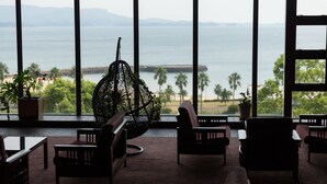 A room with large windows overlooking a body of water, a hanging chair, and several seating areas. - Hotel Ranpu (Hirado-shi)