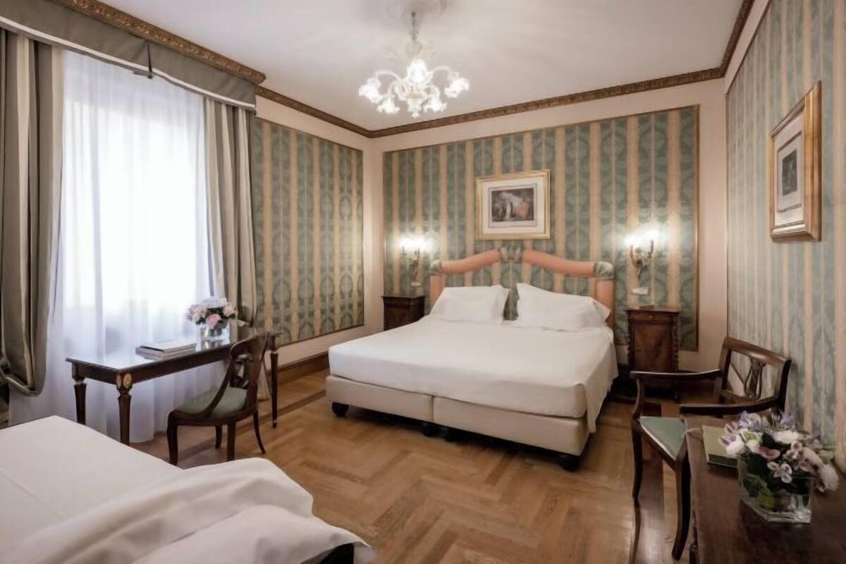 A hotel room with a large bed, two bedside tables, a desk, and a chair.