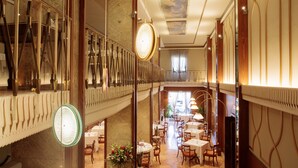 A spacious hotel lobby with a high ceiling, marble walls, and a central staircase.