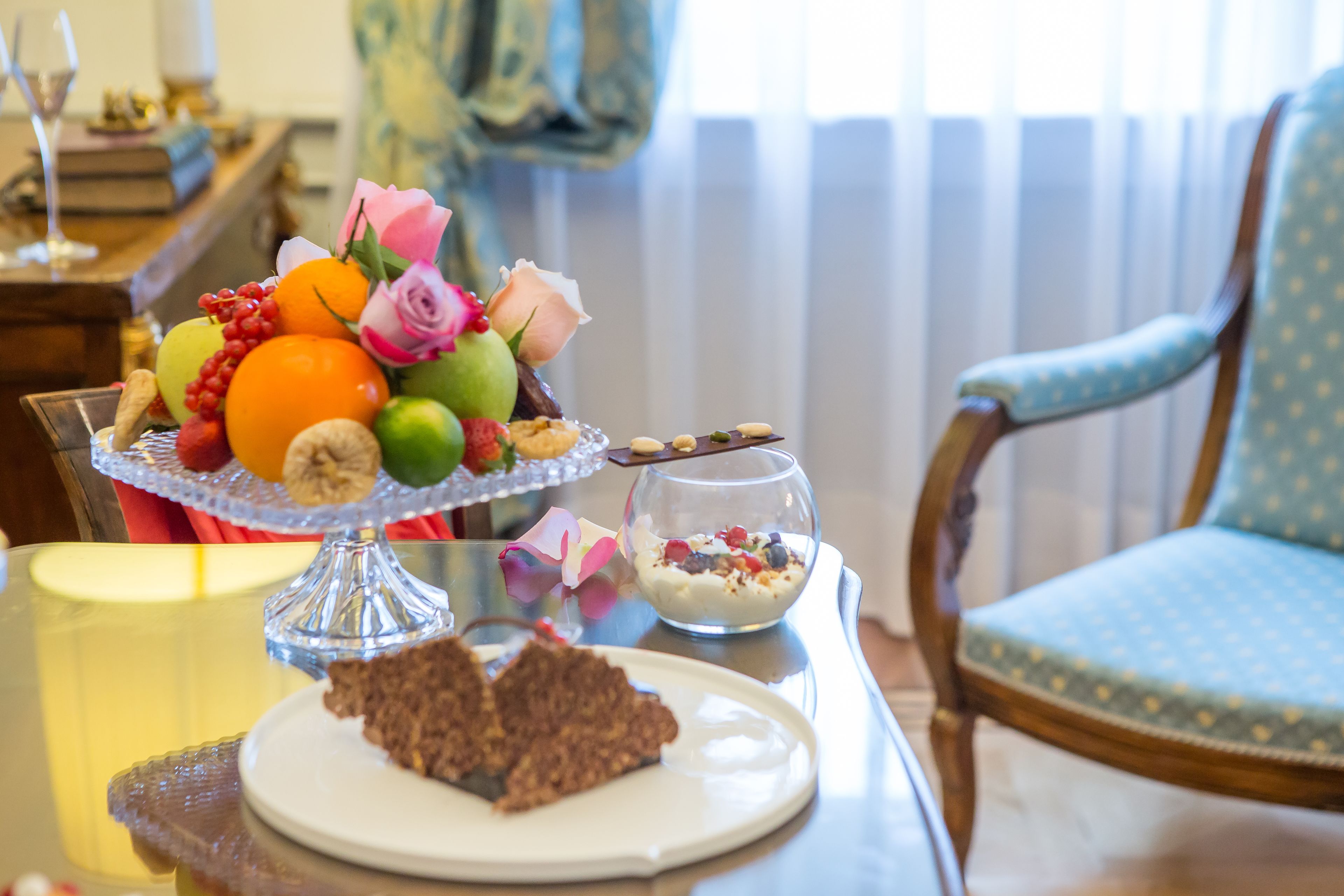 Ein Esstisch mit Obstschale, einer Glaskugel mit Joghurt und einem Teller mit Schokoladendessert.