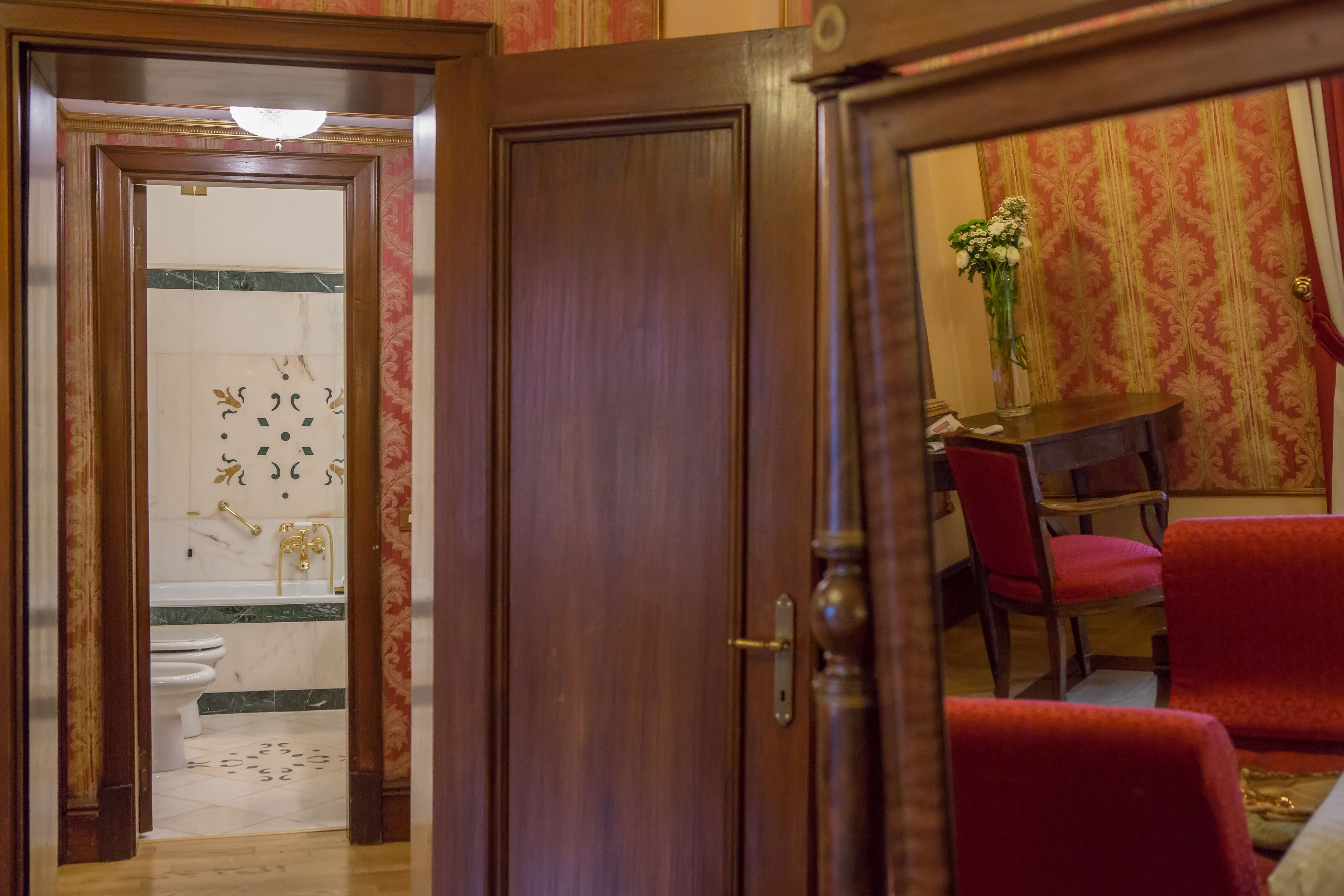A wooden door leading to a bathroom with a toilet and a shower area.