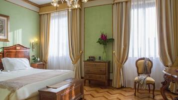 Ein Hotelzimmer mit Bett, Nachttisch aus Holz, Kommode, Stuhl und Tisch.