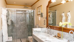Un baño moderno con ducha de vidrio, tocador doble y un espejo grande.