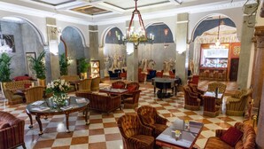 A spacious lobby with checkered flooring, multiple seating areas, and a bar.