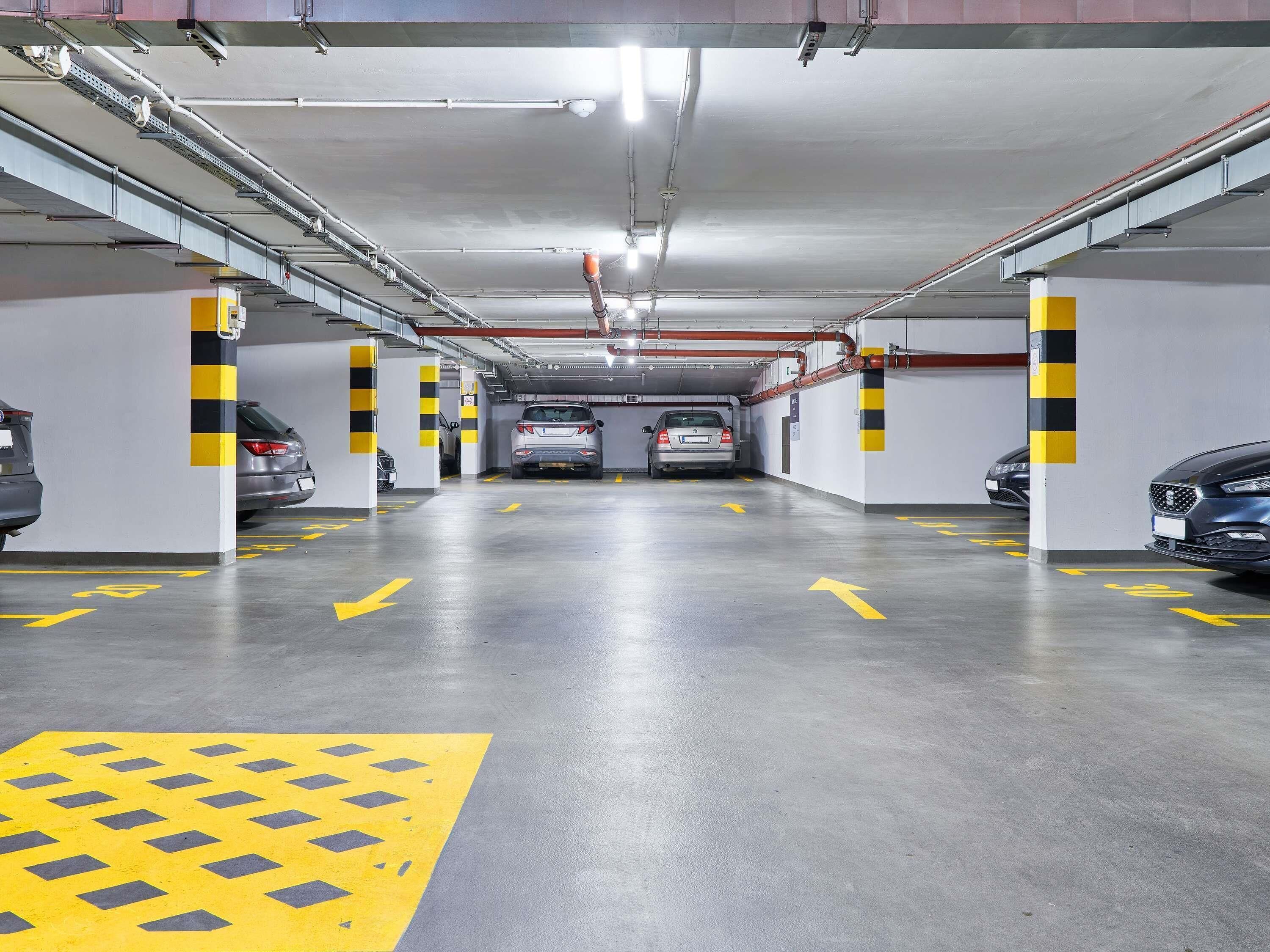 A multi-level parking garage with clear directional arrows on the floor, and cars parked in designated spaces.