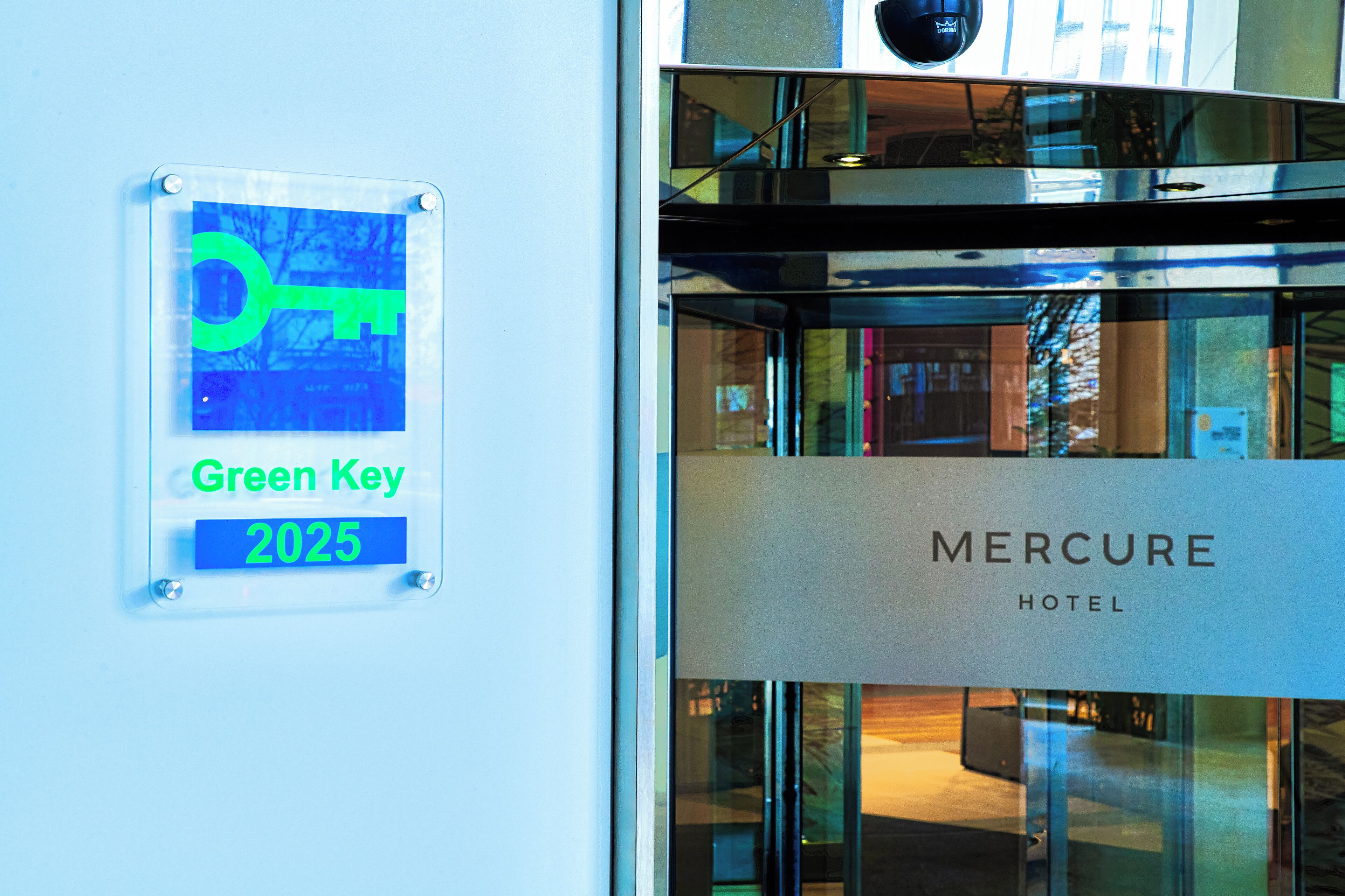 A sign with "Green Key 2025" and "Mercure Hotel" on a building facade.