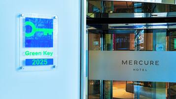 A sign with "Green Key 2025" and "Mercure Hotel" on a building facade.