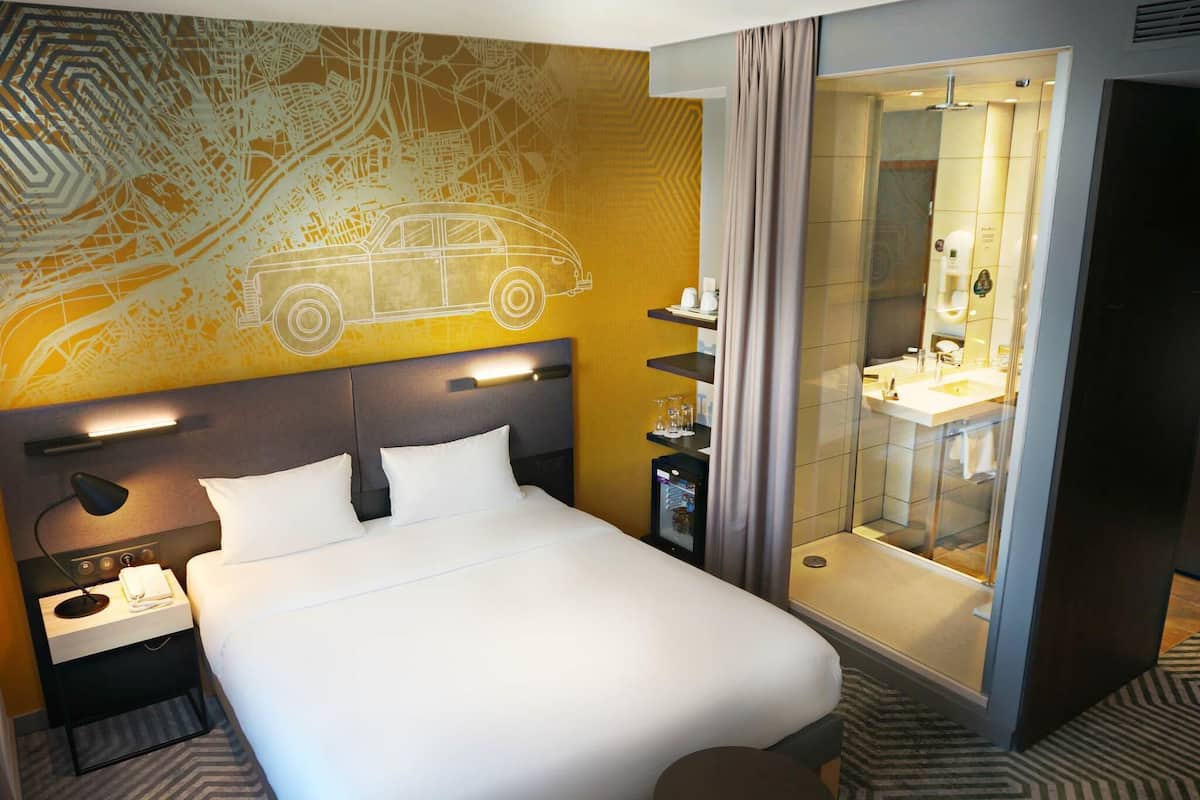 Une chambre d’hôtel avec un lit, une table de chevet, une lampe et une carte accrochée au mur.
