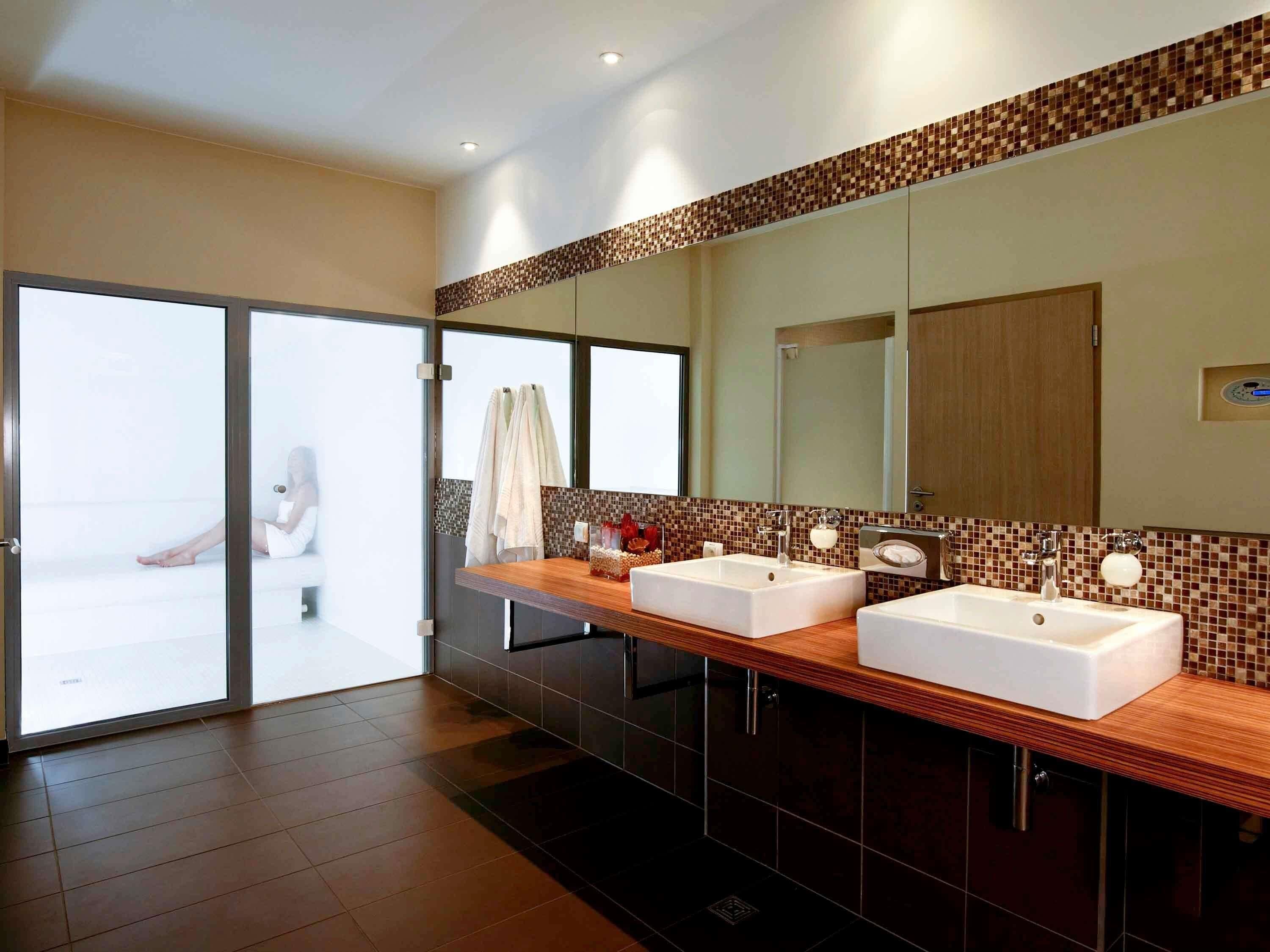 A modern bathroom with two sinks, a large mirror, and a sliding glass door leading to a balcony.
