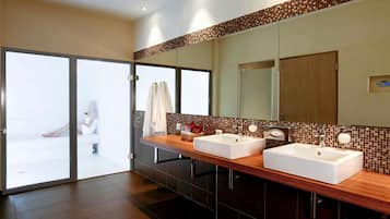 A modern bathroom with two sinks, a large mirror, and a sliding glass door leading to a balcony.