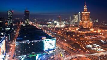Une vue nocturne d’une ville, avec des bâtiments illuminés, une tour imposante et un grand panneau publicitaire.
