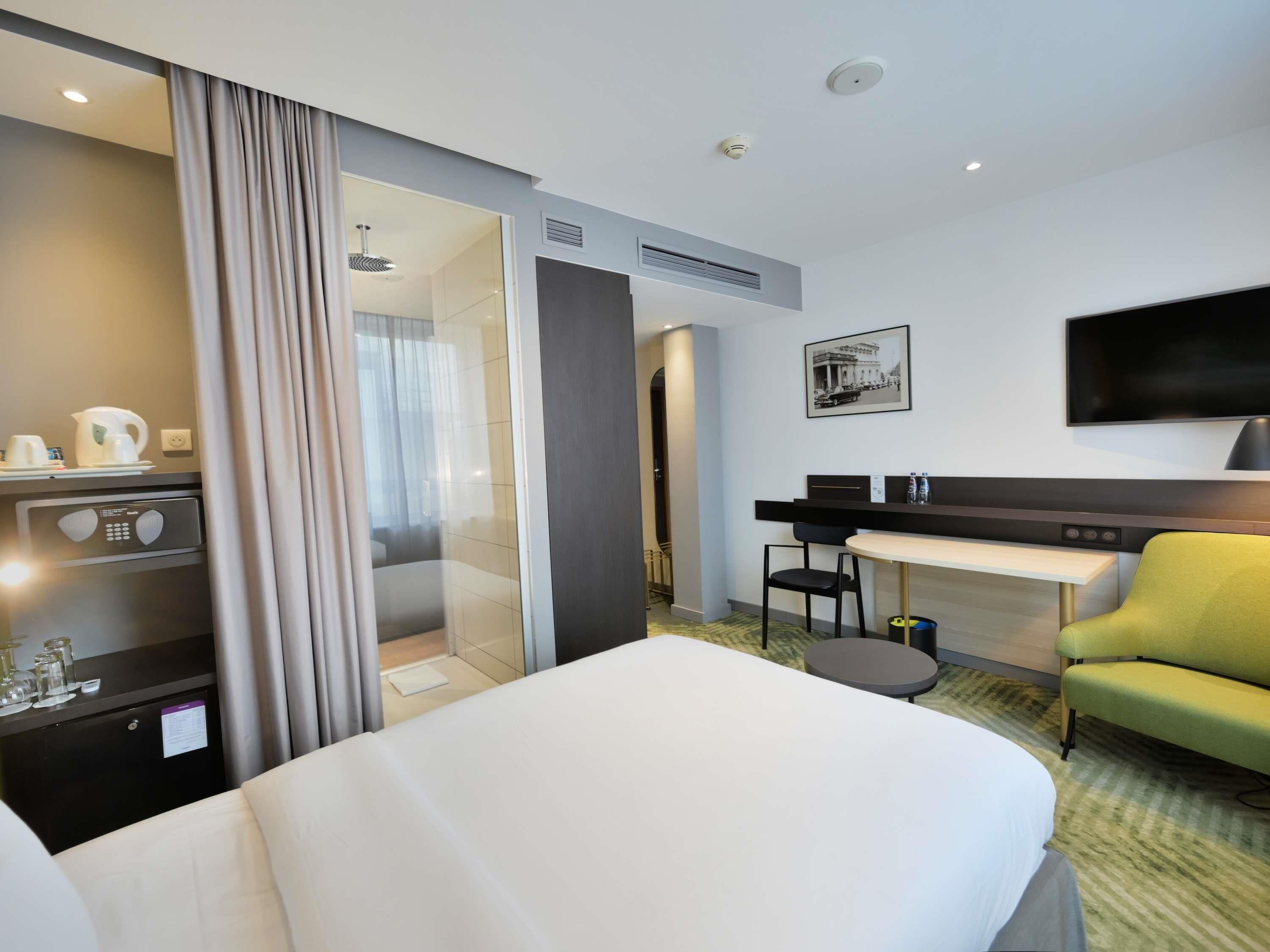 Habitación de hotel con cama, escritorio, silla, televisión y espacio para café.