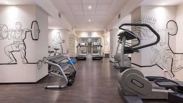 Un gimnasio con equipamiento de ejercicio, un espejo grande y un reloj.