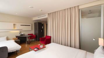 Una habitación de hotel con una cama, un escritorio, una silla y una pequeña mesa con una silla roja.