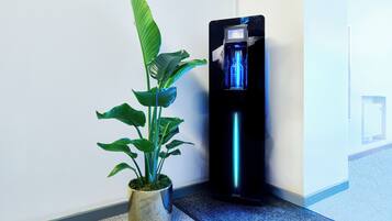 A potted plant next to a black water dispenser with a blue light.