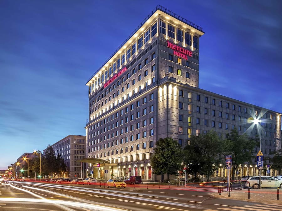 Un hotel de varios pisos con un llamativo letrero 'Mercure Hotel', que presenta un diseño arquitectónico moderno con techo plano y ventanas amplias.