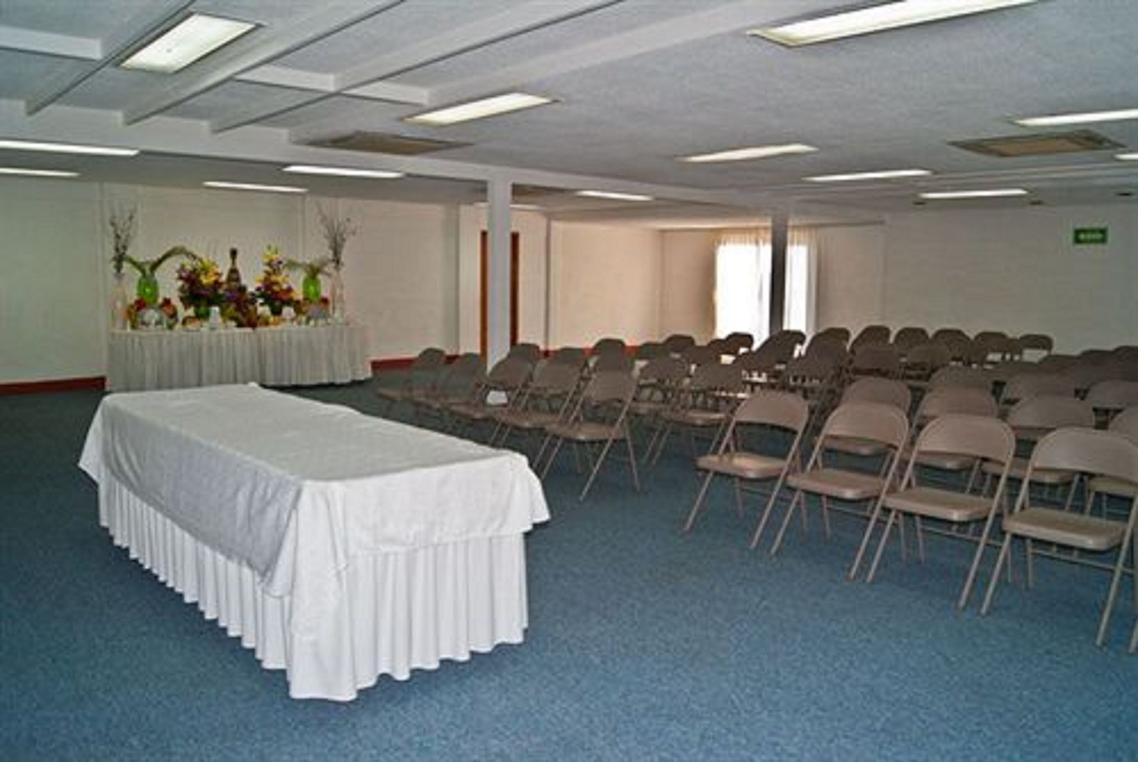 A conference room with a long table, rows of chairs, and a floral arrangement.
