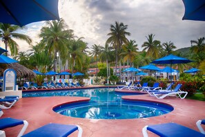 Relax by the pool surrounded by palm trees and lounge chairs.