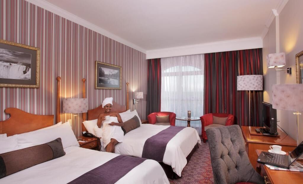 Ett hotellrum med två sängar, en sittgrupp med en fåtölj, ett skrivbord och en tv.