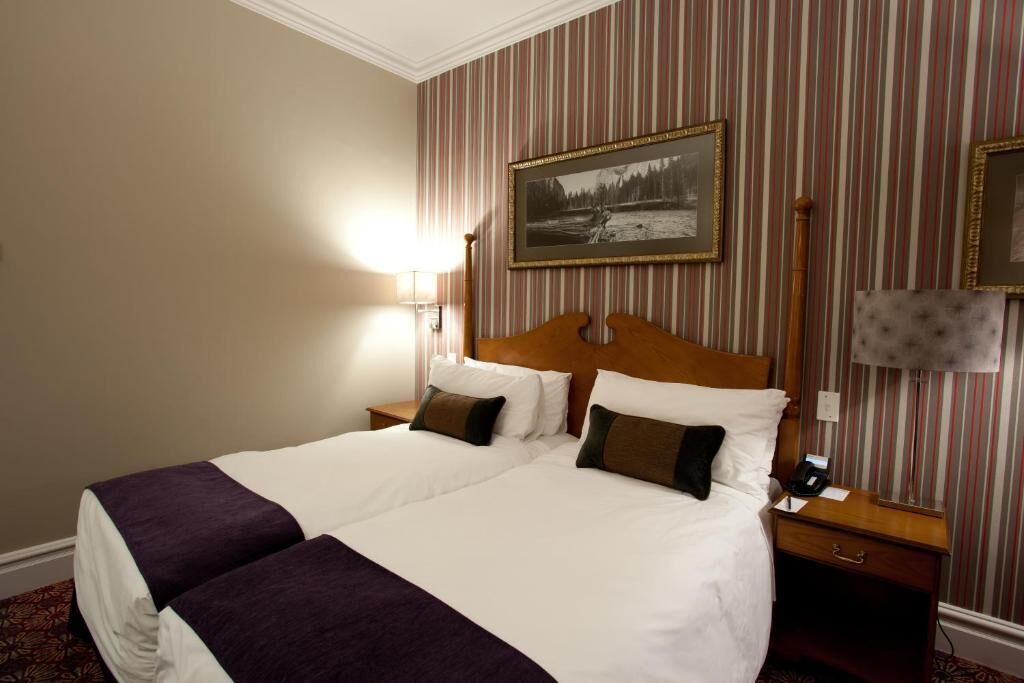 A hotel room with a large bed, two bedside tables, a lamp, and a framed picture on the wall.