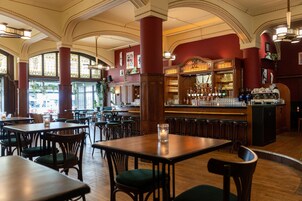 A spacious restaurant with high ceilings, large windows, and a bar area.
