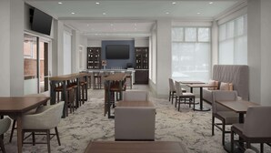 Un amplio vestíbulo de hotel con varias zonas de estar, un bar y una gran pantalla de televisión.