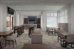 Um amplo hall de hotel com várias áreas de estar, um bar e uma grande tela de televisão.