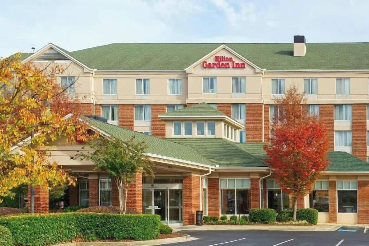 A multi-story hotel with a brick facade, a green roof, and a sign reading 'Hilton Garden Inn.'